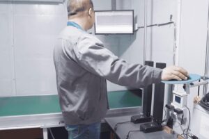 ISO 17025 certified engineer conducting 120kg cyclic load test on Contuo standing desk leg with ±0.01mm laser displacement sensors, yellow safety markers delineating EN 527-2 test zone